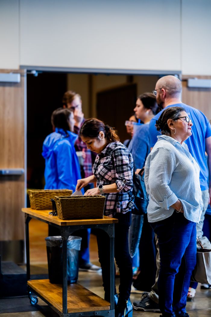 A group of adults gathered in a conversation during an indoor event with a focus on community interaction.